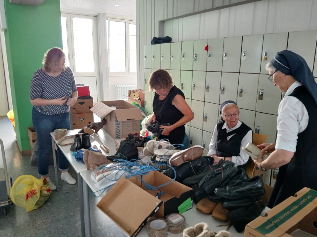 Mehrere Helferinnen, darunter zwei Ordensschwestern, sortieren und bündeln gespendete Schuhe für die Aktionstag-Sammlung Äthiopien 2025.
