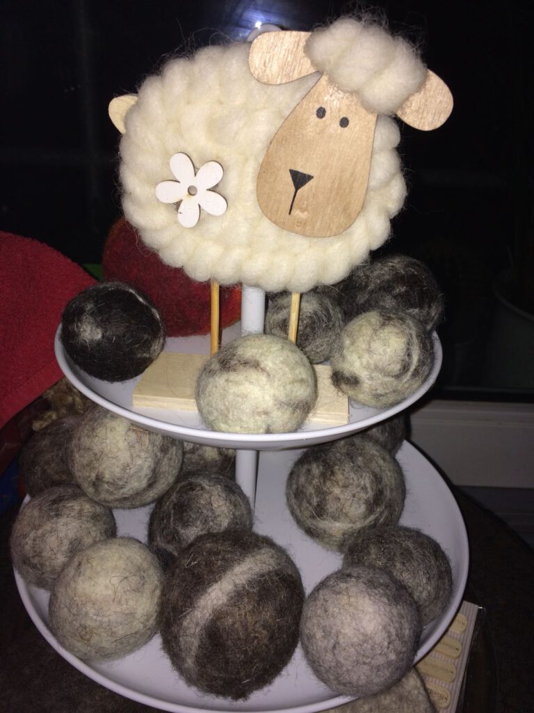 Ein niedliches Schaf thront über einem Berg von Wollbällen