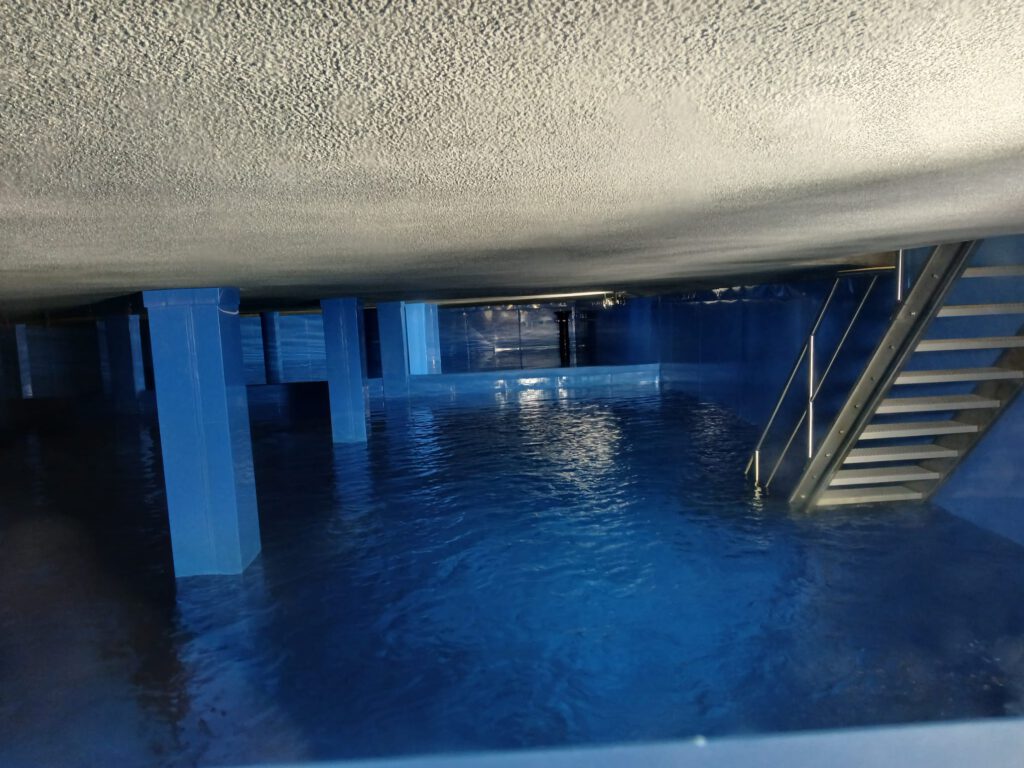 Innenansicht eines Hochbehälters der Sindelfinger Wasserversorgung mit blauem Trinkwasserbecken und Zugangstreppe.